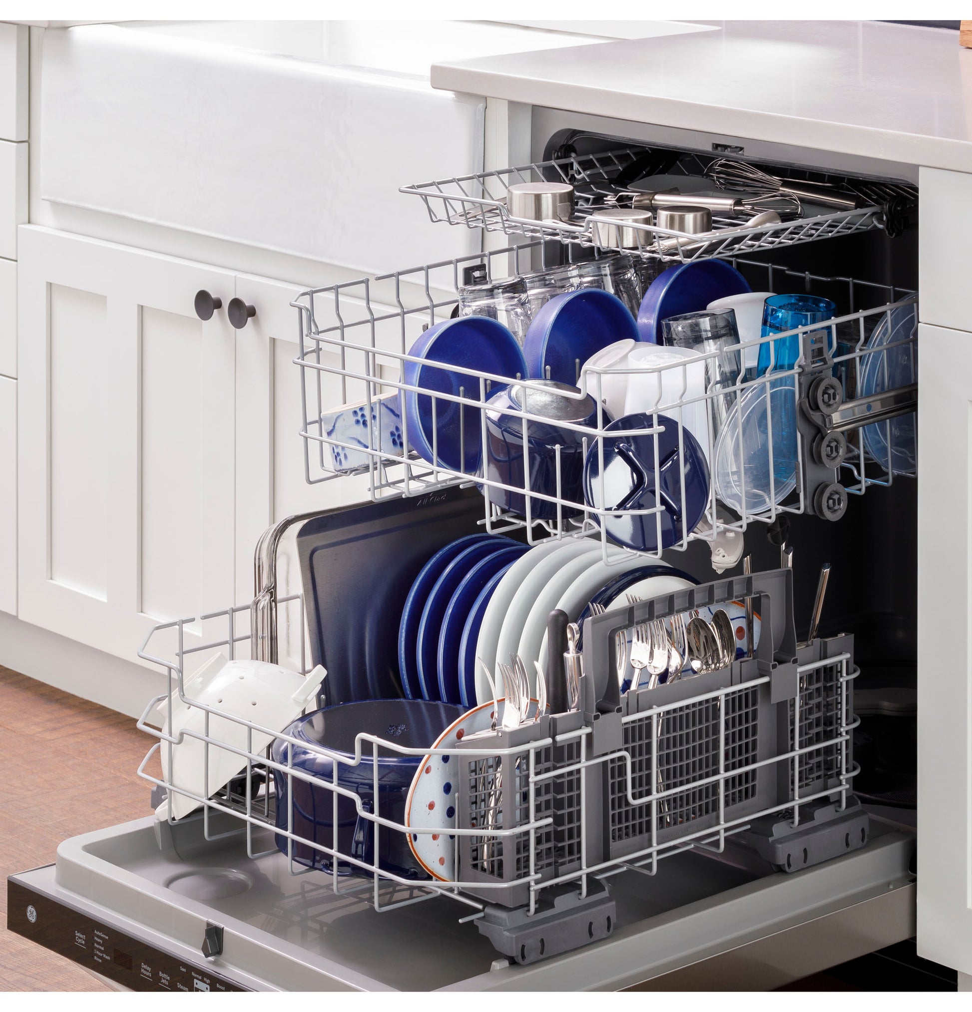 Open dishwasher loaded with blue and white plates, cups, and silverware in modern kitchen appliance setting
