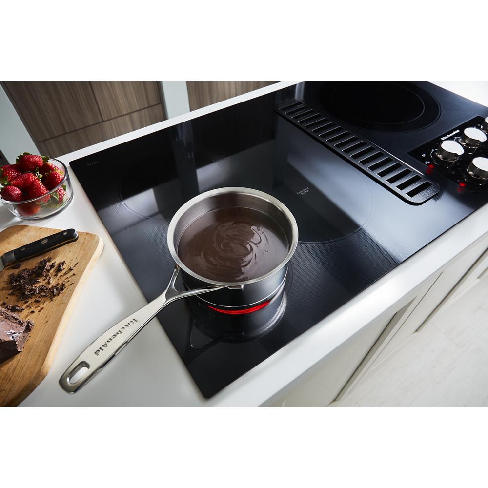 Electric cooktop with integrated downdraft vent and five cooking elements, styled for modern kitchen spaces.