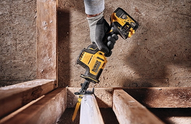 Person wearing gloves using DEWALT Atomic 20V MAX cordless one-handed reciprocating saw for wood cutting tasks