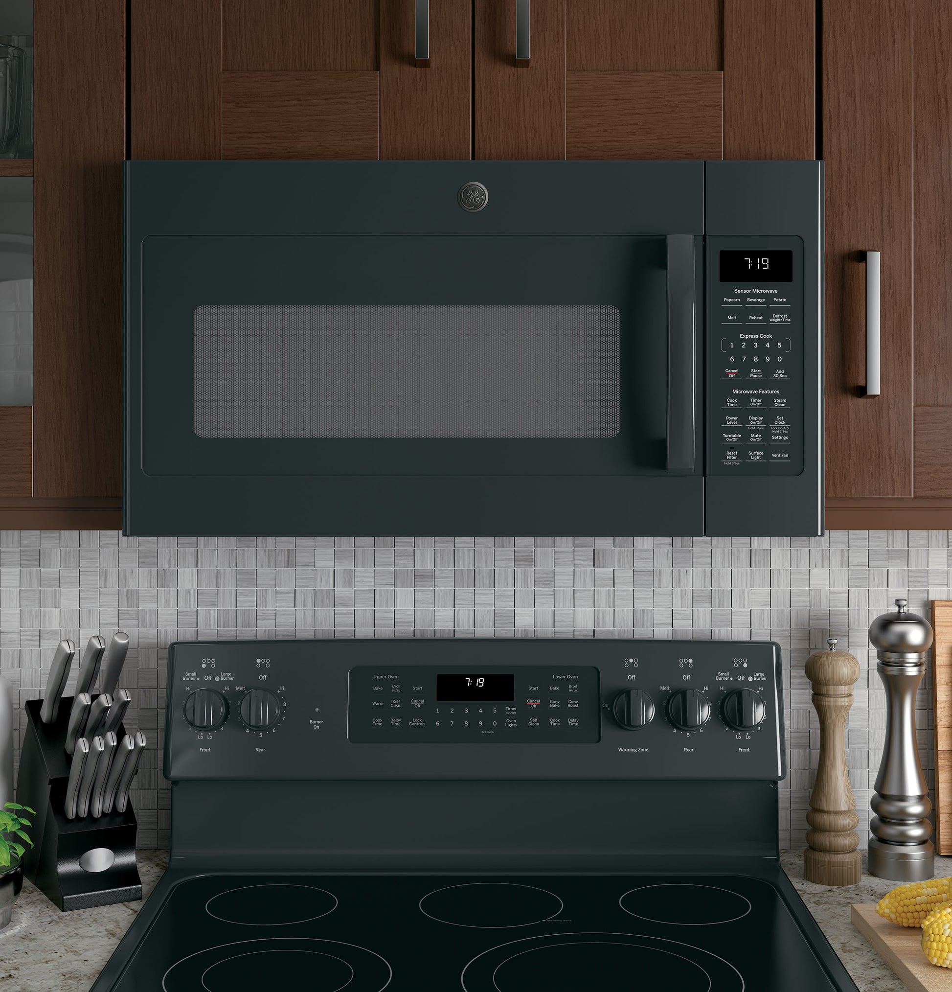 Matte black over-the-range sensor microwave with digital display installed above matching electric range in kitchen appliances