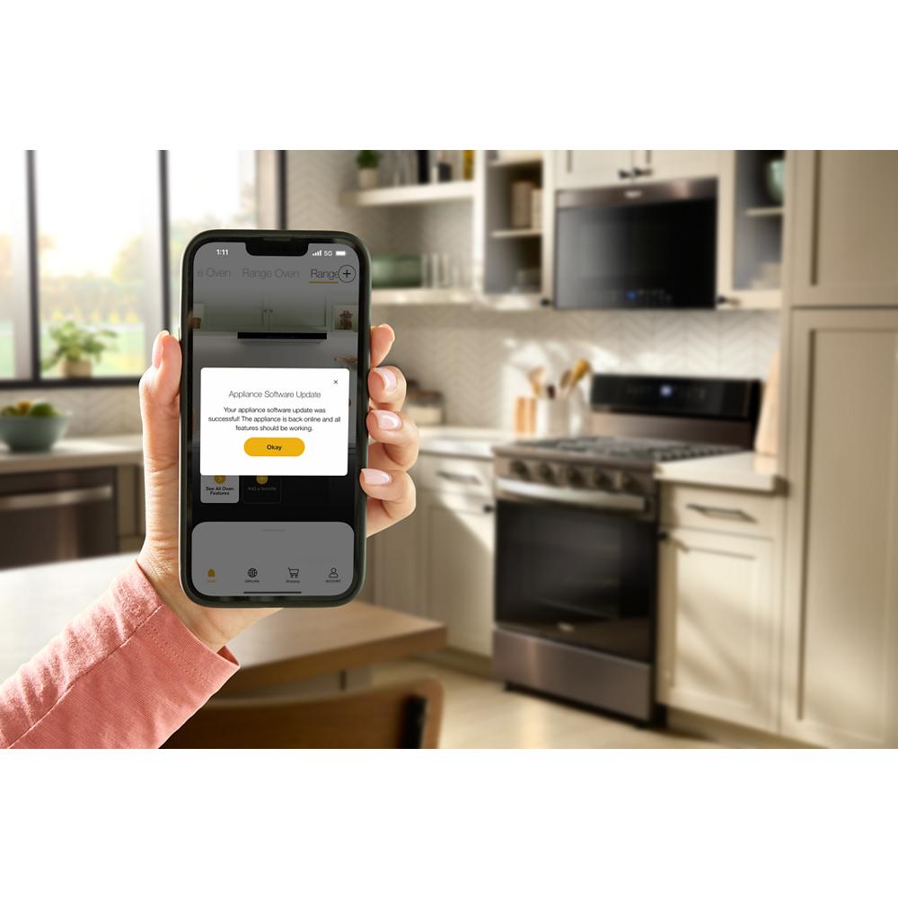 hand holding smartphone displaying appliance software update message with modern gas range in kitchen background