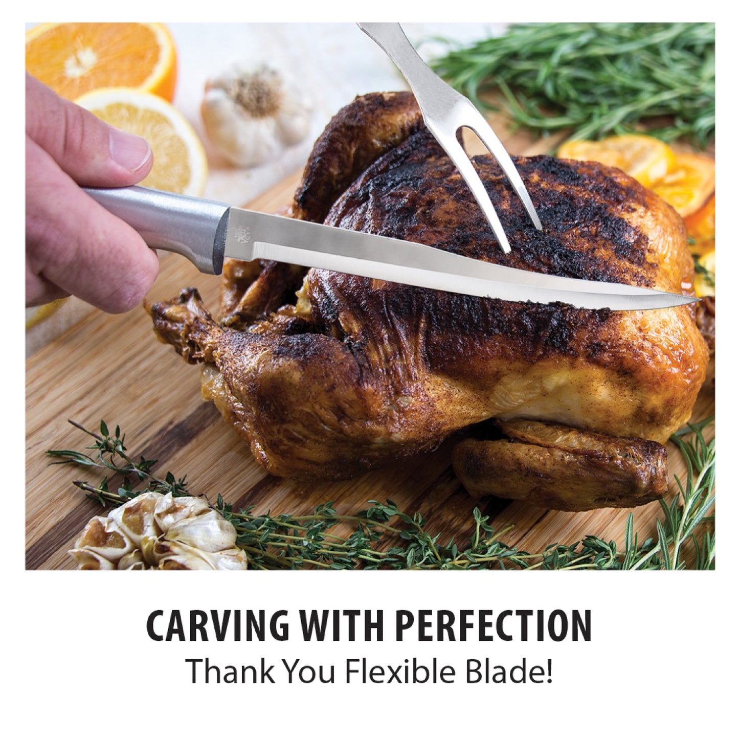 Hand holding stainless steel boning knife carving roasted chicken on wooden board with herbs and garlic from kitchenware collections