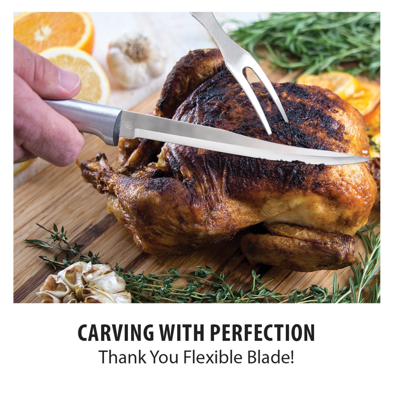 Hand holding stainless steel boning knife carving roasted chicken on wooden board with herbs and garlic from kitchenware collections