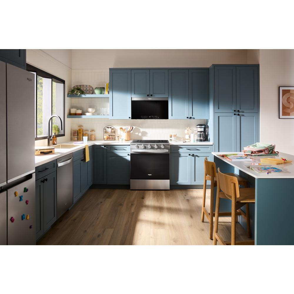 Modern kitchen featuring blue cabinetry with a stainless steel slide-in gas range and hardwood flooring in home improvement setting