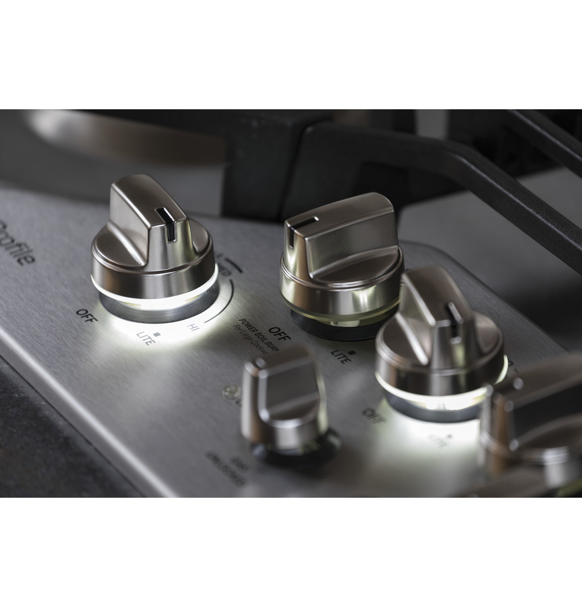 Close-up of stainless steel control knobs with light indicators on built-in gas cooktop from kitchen appliance collection