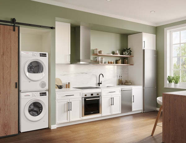 Stacked white front load washer and dryer in modern kitchen with green walls, wood flooring, and stainless appliances