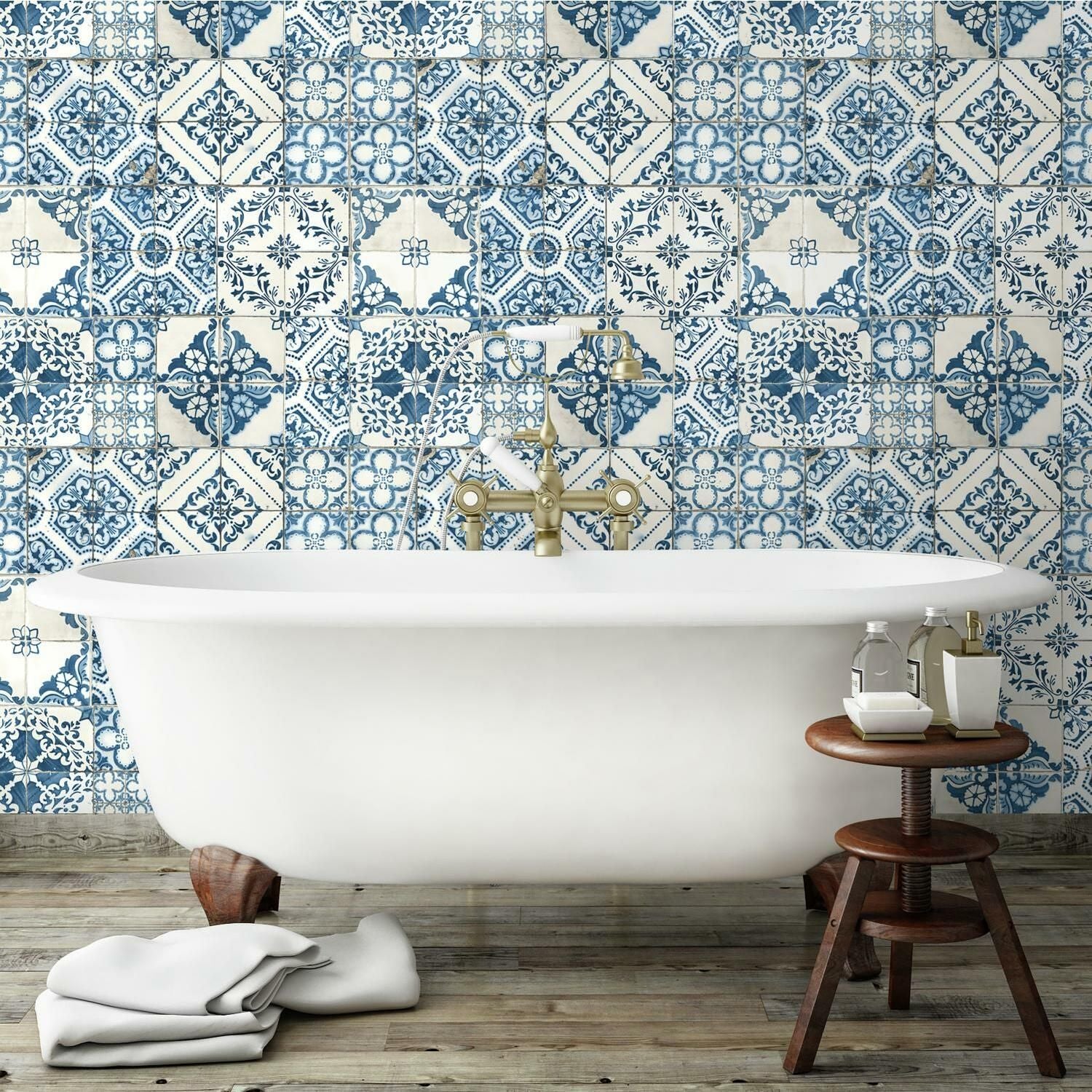 Blue and white Mediterranean tile patterned peel and stick wallpaper behind vintage clawfoot bathtub in bathroom decor