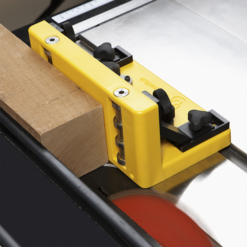 Yellow dual roller guide with adjustable knobs supporting wood on a table saw, part of saw accessories and tool collections