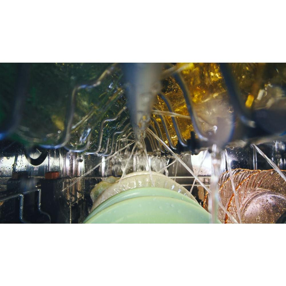 Interior view of dishwasher with water jets spraying plates and glassware inside stainless steel tub from KitchenAid appliances collection
