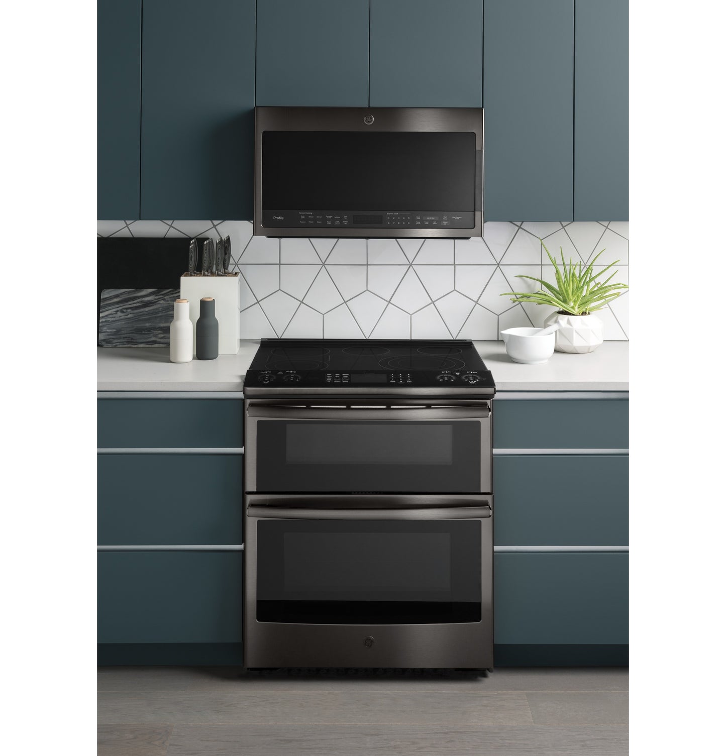 Over-the-range sensor microwave in black stainless steel above smooth-top double wall oven in modern kitchen setup
