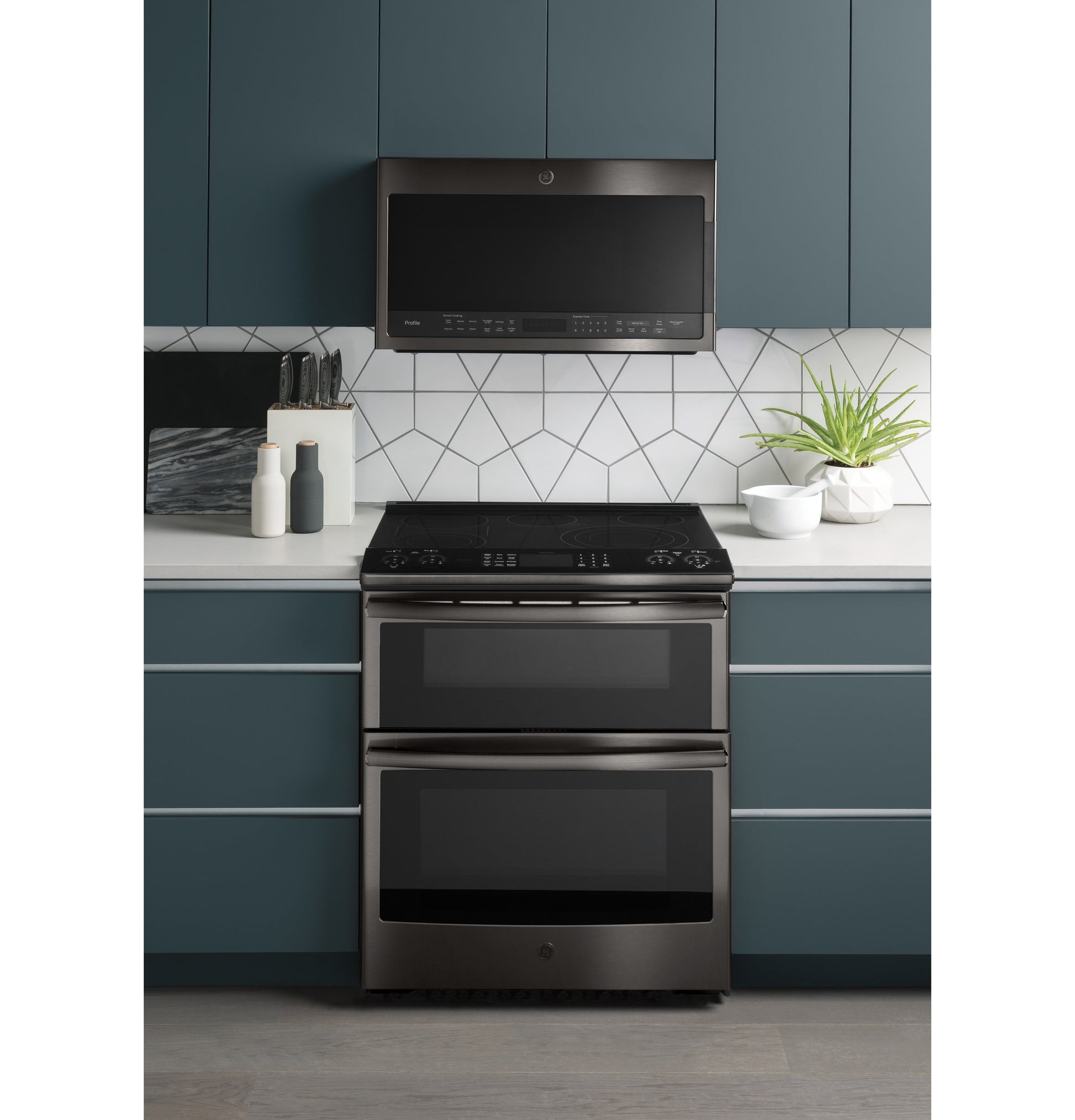 Over-the-range sensor microwave in black stainless steel above smooth-top double wall oven in modern kitchen setup