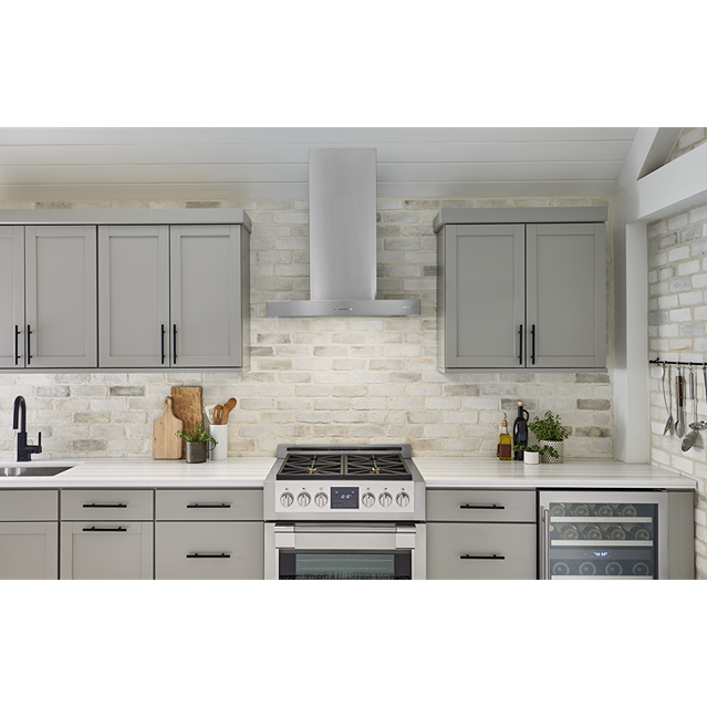 Contemporary stainless steel chimney hood with LED lighting above gas range in modern kitchen from Over the Range Hoods collection