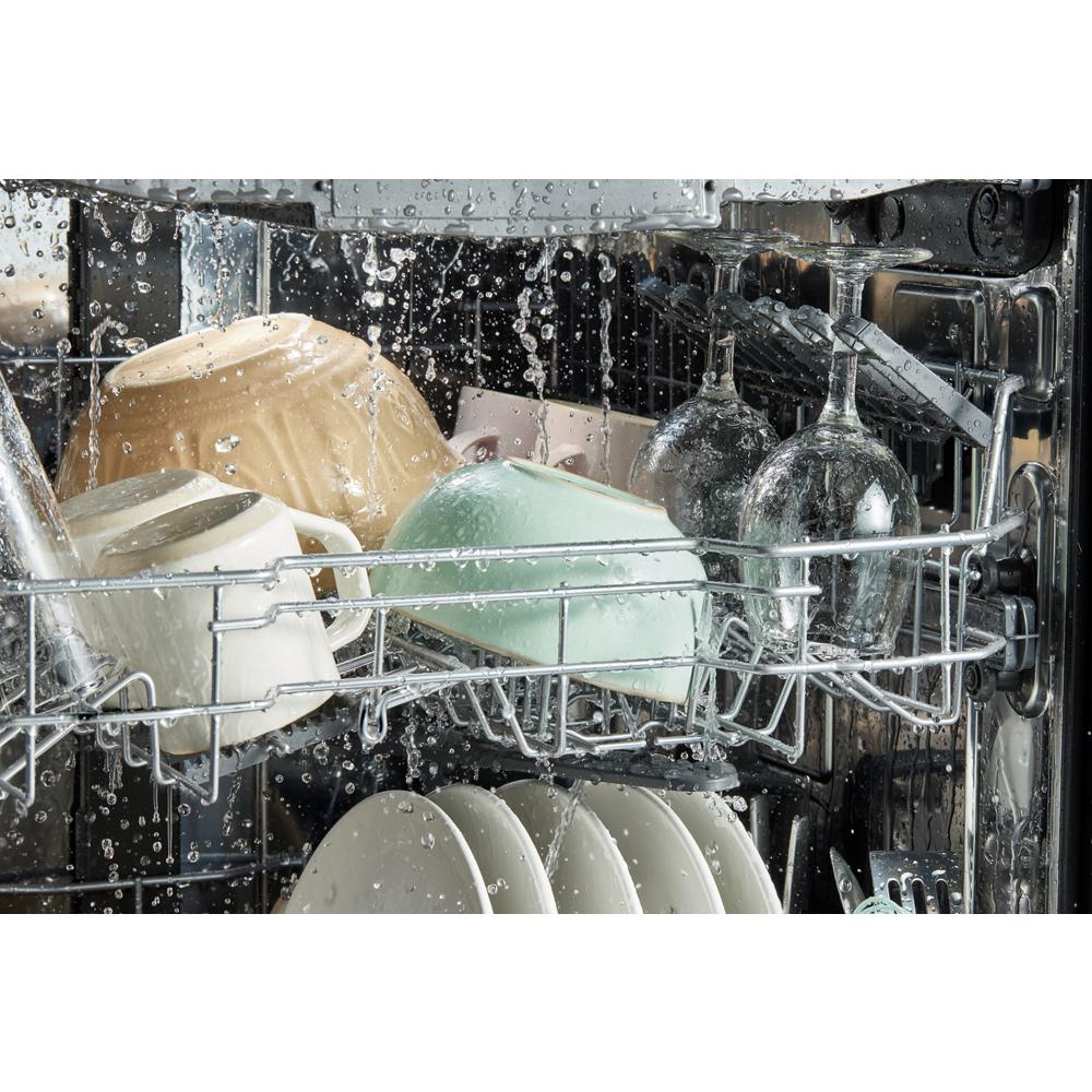 Interior view of dishwasher mid-cycle with water spraying over plates, cups, and glassware in kitchen appliances collection