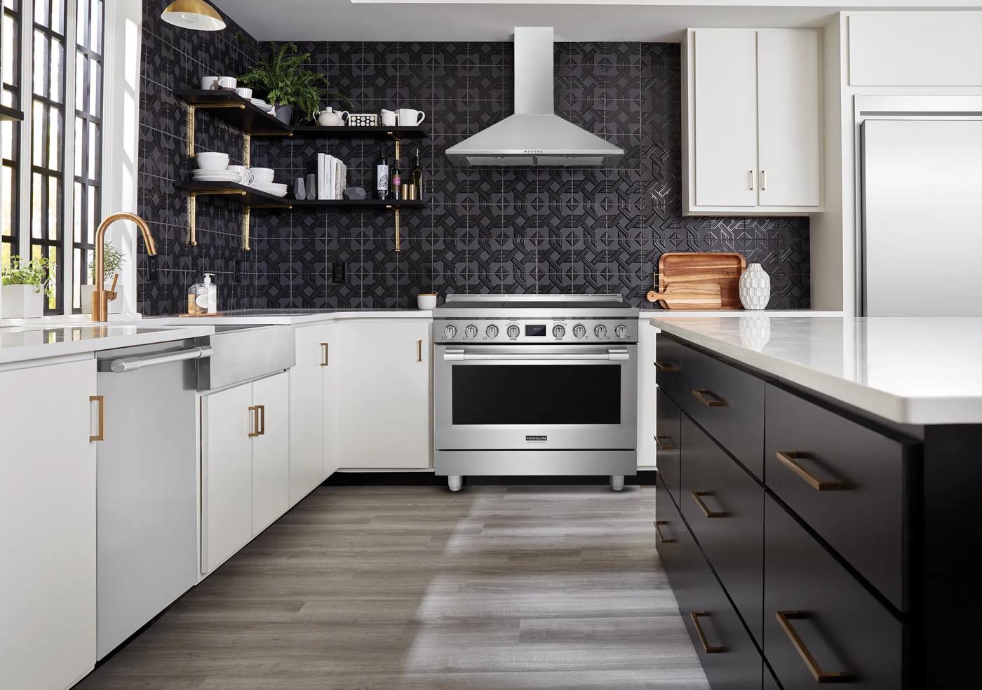 Modern kitchen with a 36-inch dual-fuel freestanding range, white cabinetry, black island, and patterned backsplash wall