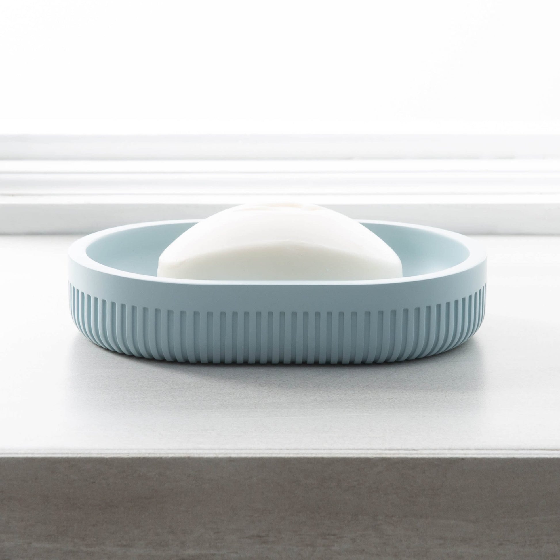 Blue resin soap dish with textured sides holding white soap, suitable for bathroom and bath accessory collections