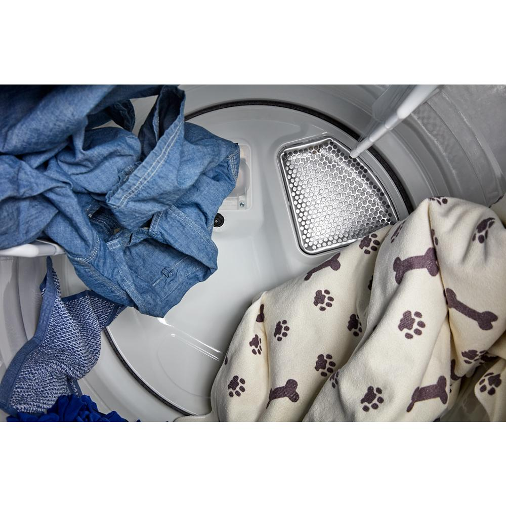Interior view of electric dryer with pet hair-trapping blanket and denim clothes in home appliances collection