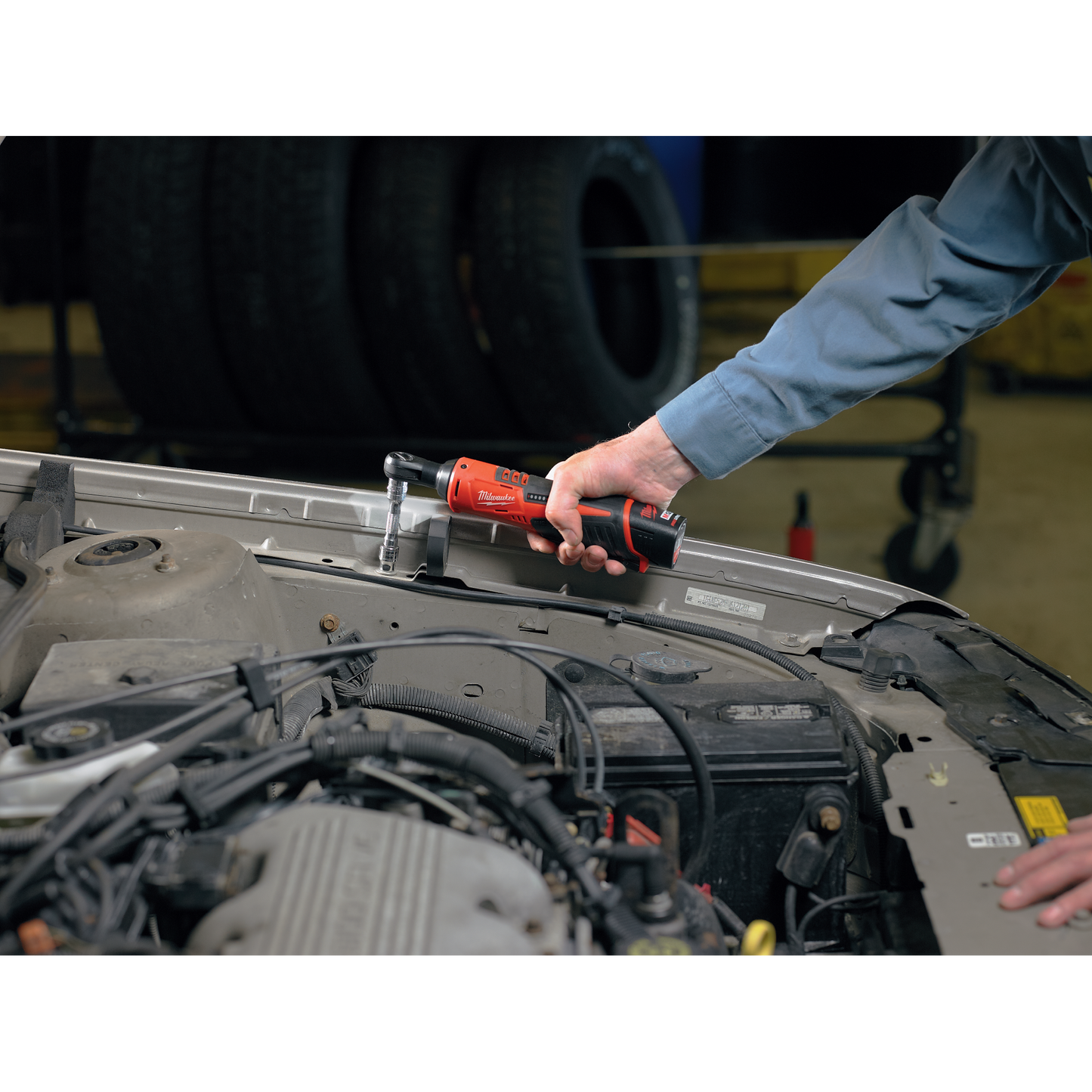 Hand using Milwaukee M12™ 3/8" cordless ratchet on car engine for automotive tools and home improvement task