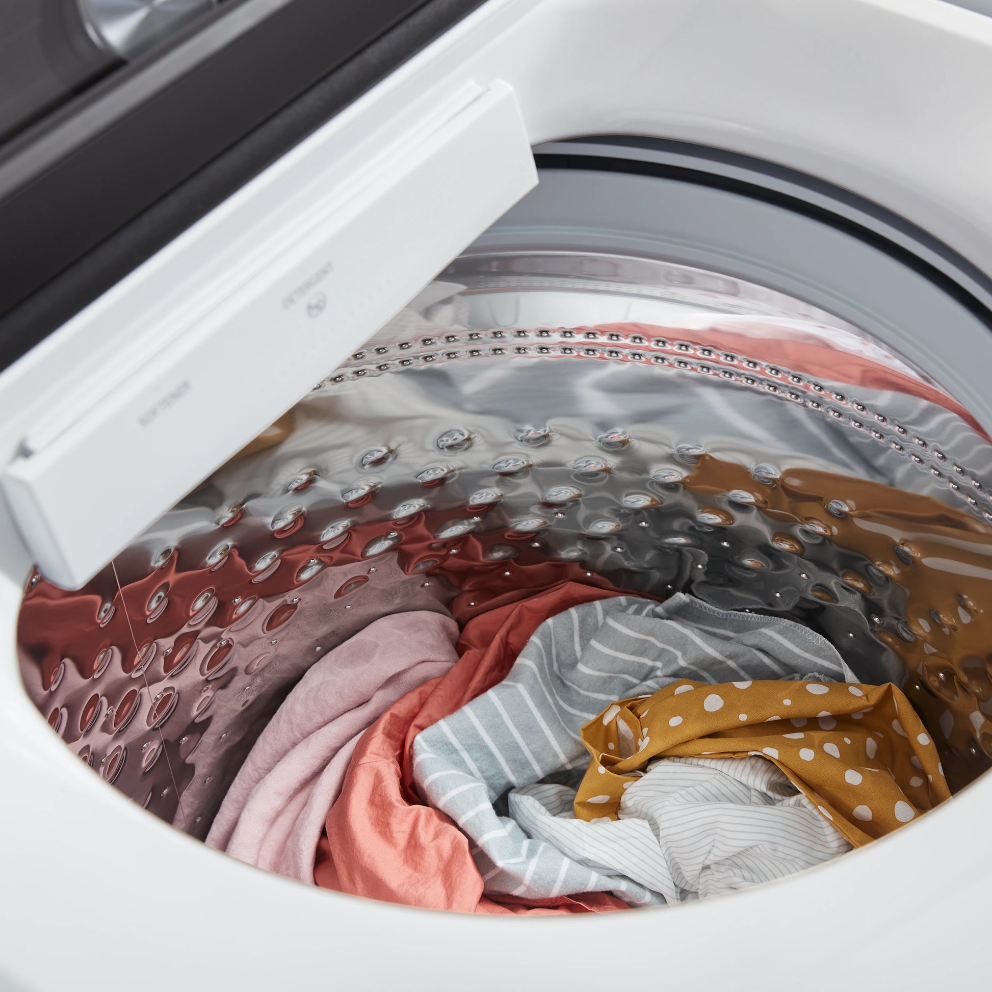 Open top view of white long vent electric dryer showing mixed laundry inside drum in home appliance setting