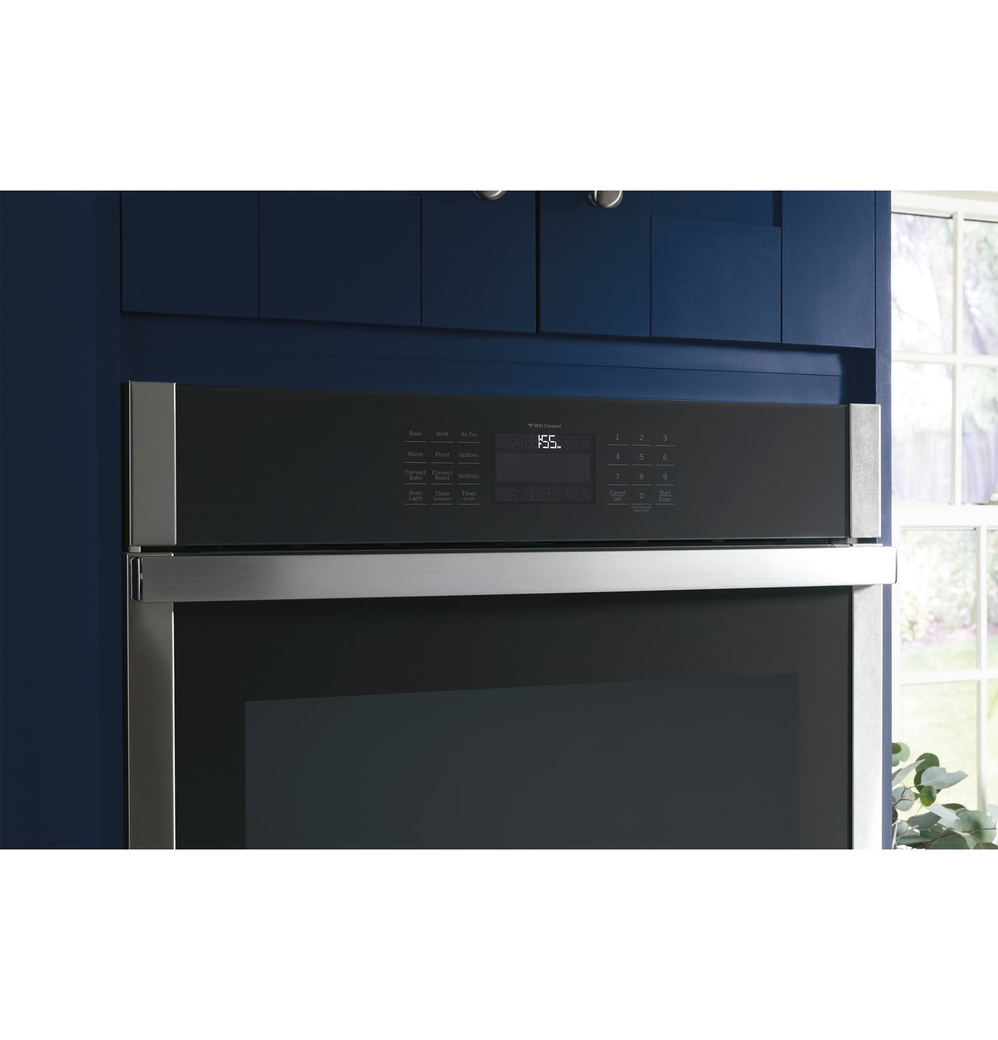 Built-in stainless steel convection double wall oven with digital control panel in dark blue kitchen cabinetry