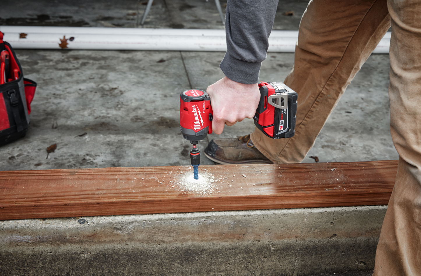Person using a red cordless impact driver on wood board in a home improvement and power tools setting