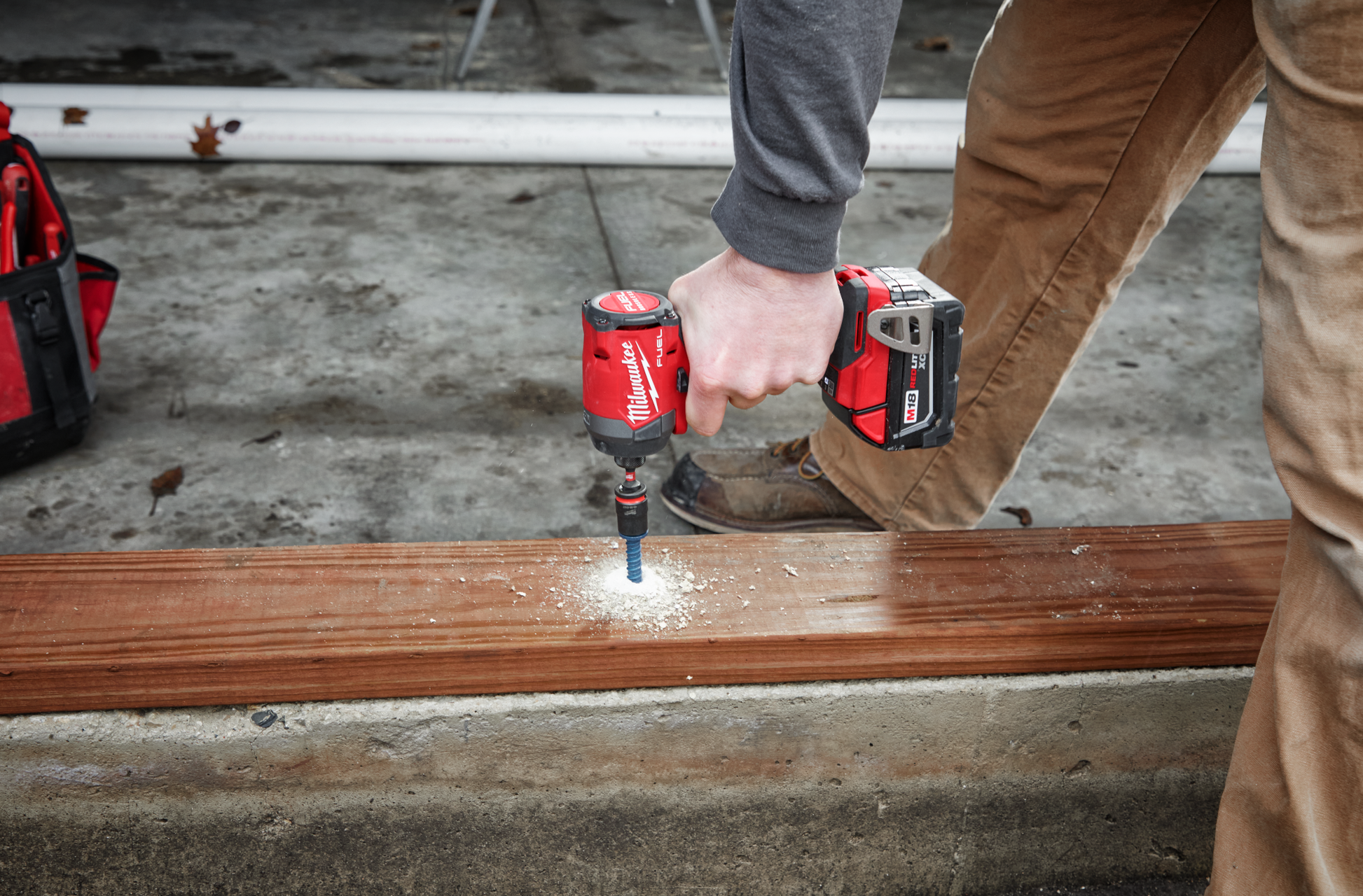 Person using a red cordless impact driver on wood board in a home improvement and power tools setting