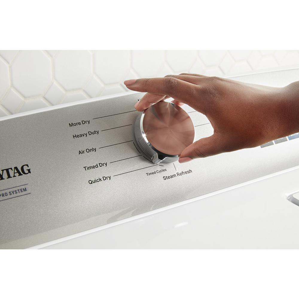 Hand adjusting cycle selector knob on silver control panel of top load dryer in modern laundry setting