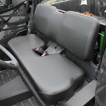 Black cushioned bench seat with seatbelt and mesh side panels in utility vehicle cabin for outdoor work tasks