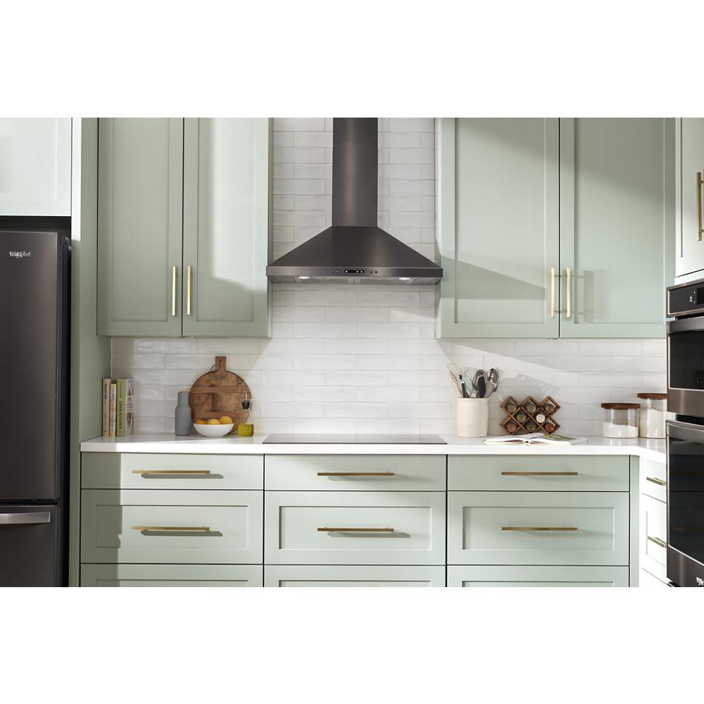 Modern kitchen with stainless steel chimney range hood mounted above white countertop and mint green cabinets