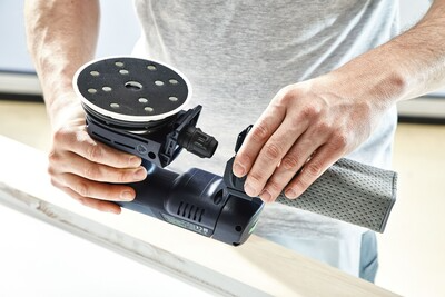 Hands attaching dust collection bag to cordless eccentric sander for home improvement and tool use