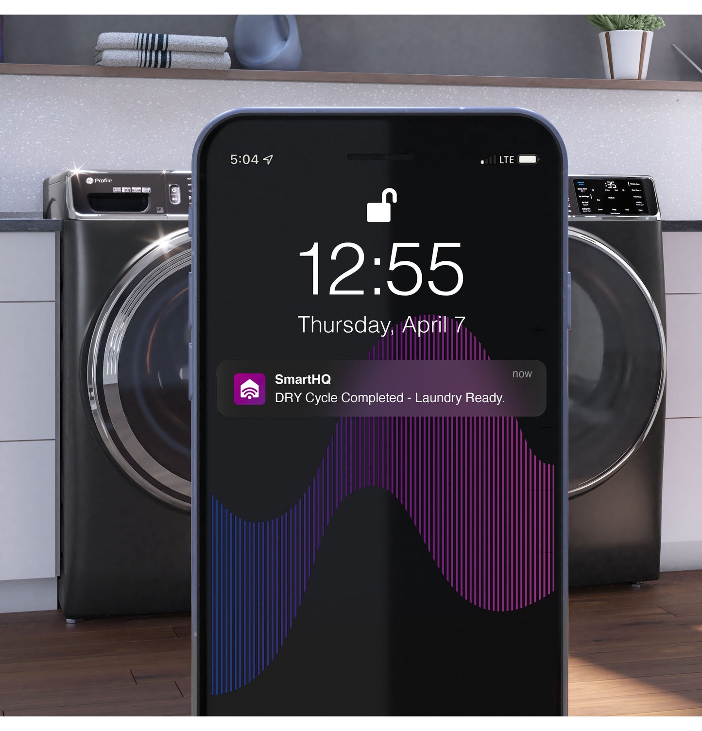Smartphone displaying laundry cycle complete alert in front of black smart front load gas dryers in appliances collection