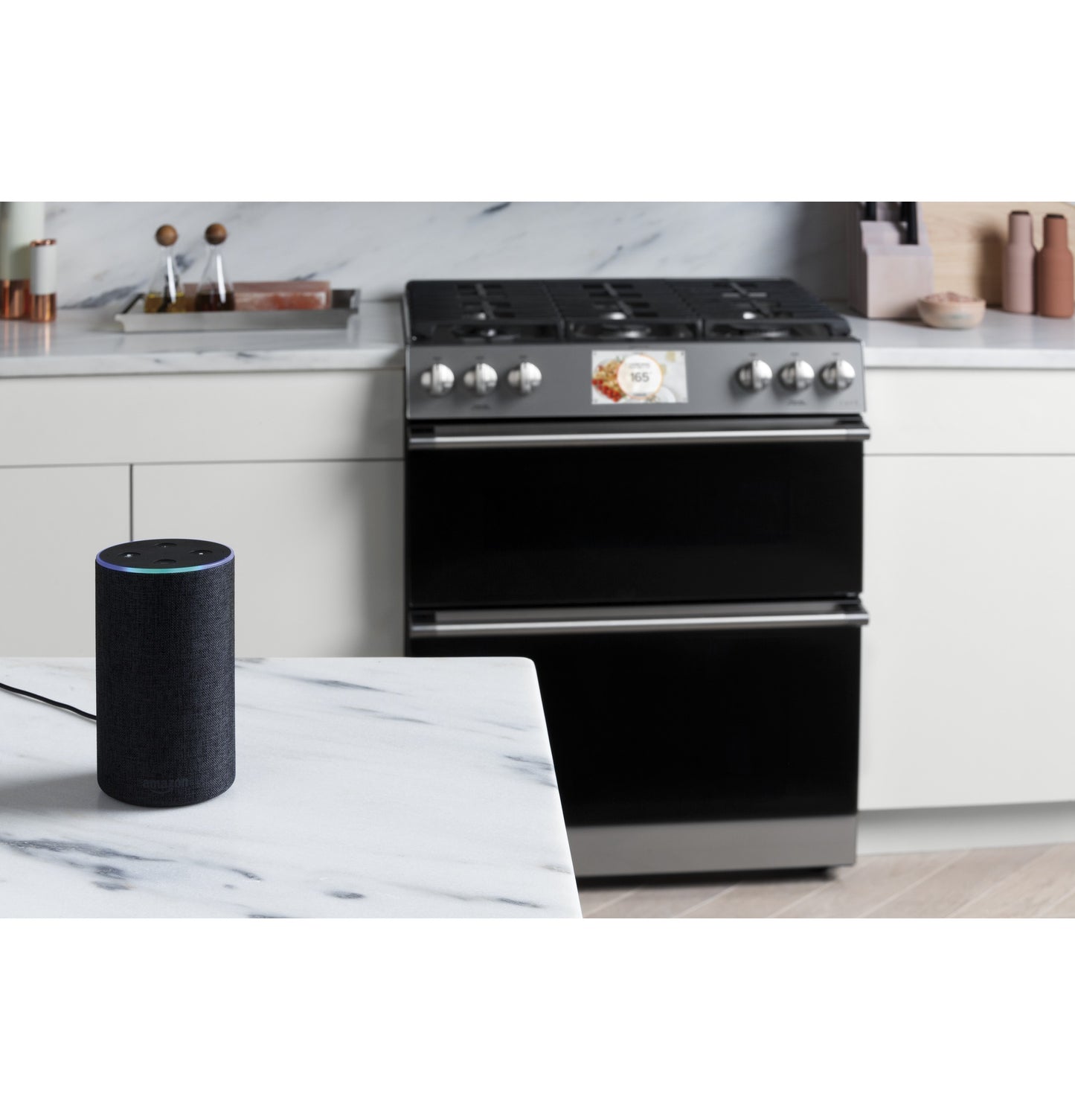 Modern kitchen scene with platinum smart gas range and voice-activated smart speaker on marble countertop