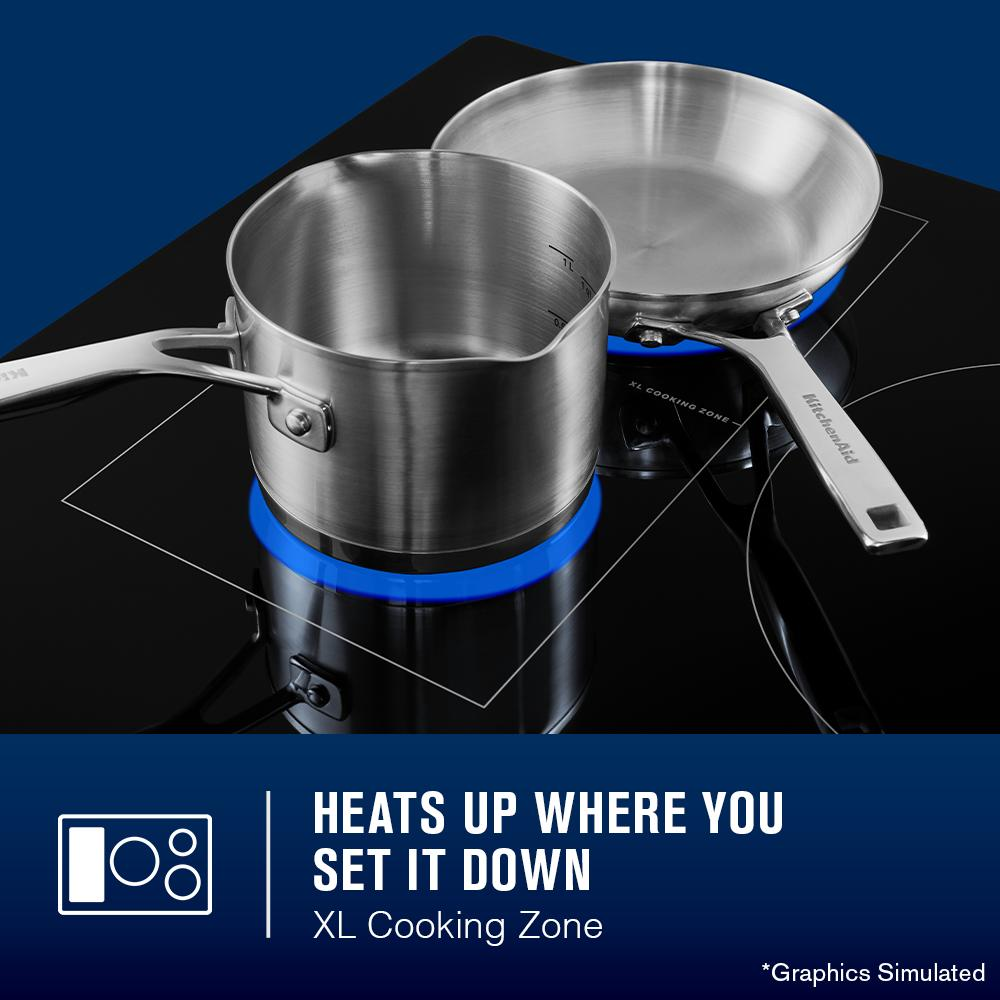 36-inch induction cooktop with XL cooking zone heating two stainless steel pans in kitchen appliance setting