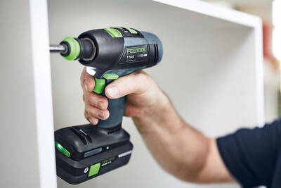 Person using a cordless Festool drill for assembling furniture in a bright home improvement setting