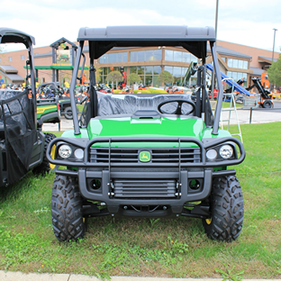 Green John Deere utility vehicle with heavy-duty tires and protective canopy for rugged outdoor work tasks