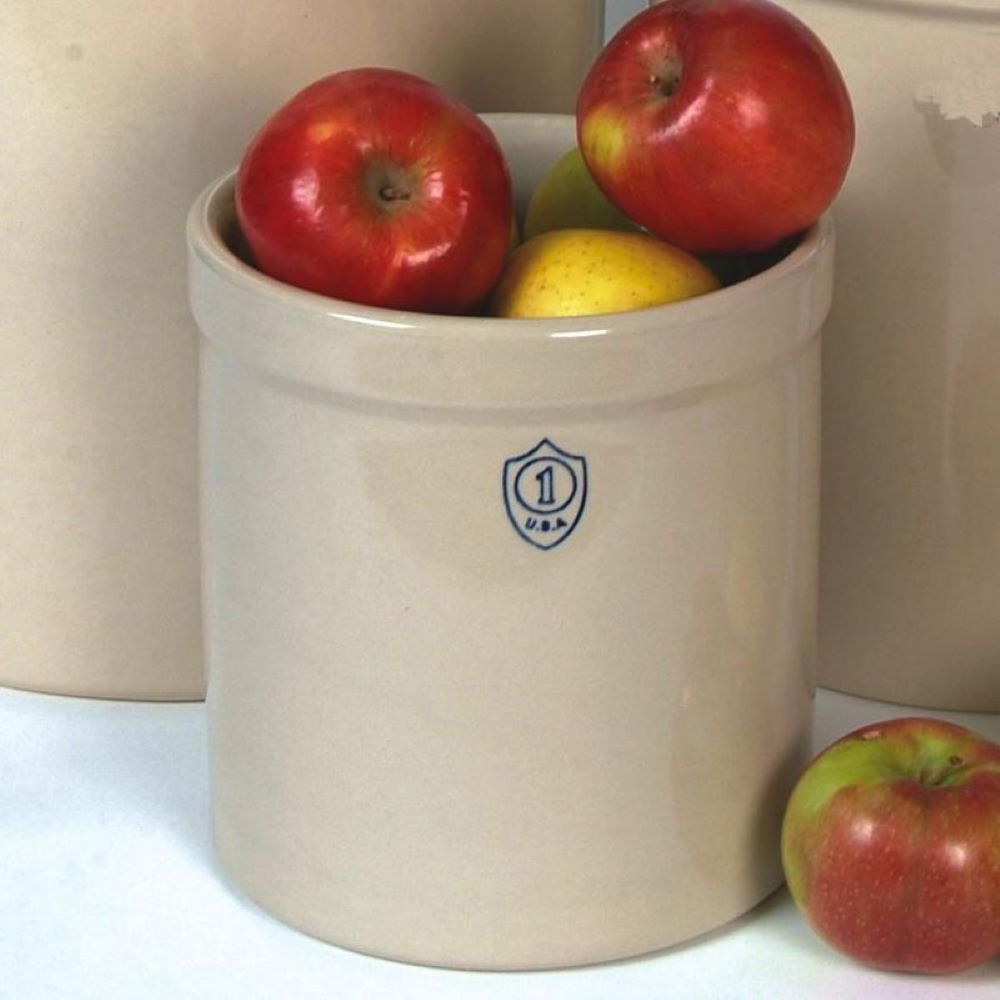 Beige stoneware crock with blue shield emblem holding red and yellow apples for kitchen or home use