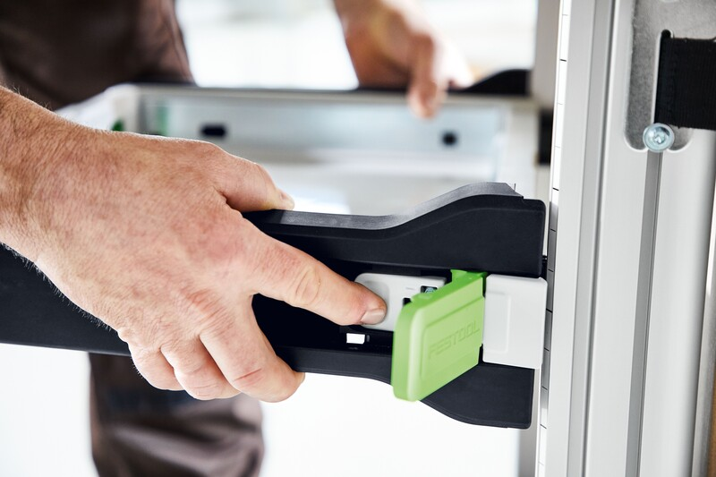 Hand adjusting green locking mechanism on black and white pull-out drawer for workshop storage organization system