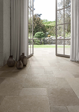 Indoor flooring with matte porcelain tiles in warm neutral tones opening to a lush outdoor garden space