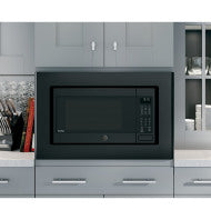 Built-in microwave trim kit in black finish installed in modern gray kitchen cabinetry for home improvement projects