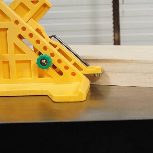 Yellow plastic woodworking gauge tool with green adjustment knob positioned on wood in power tool accessories collection