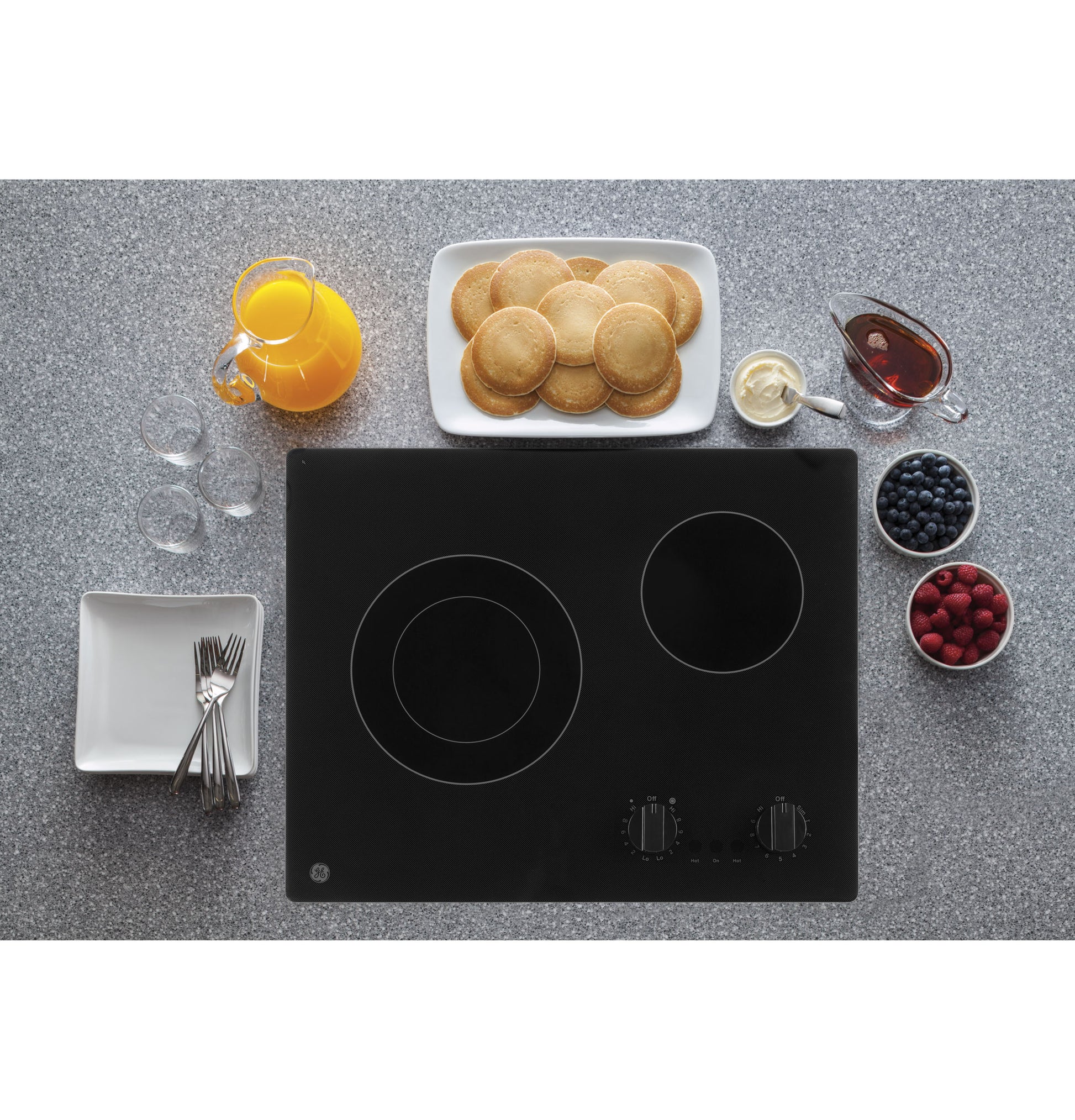 Black electric cooktop with two radiant burners and control knobs surrounded by breakfast items on countertop