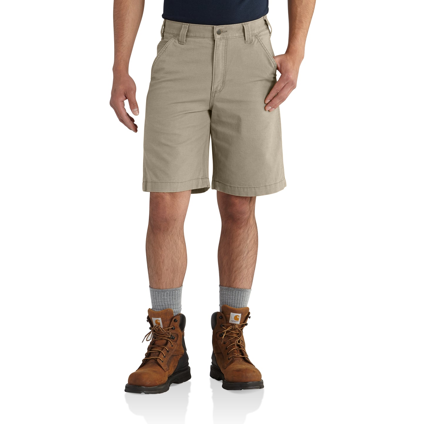 Man wearing tan rugged flex canvas work shorts paired with brown work boots and gray socks
