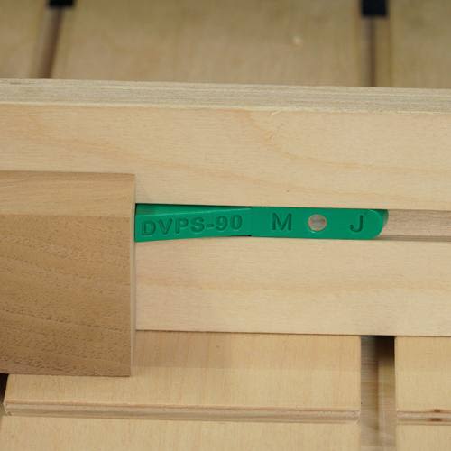 Green plastic guide strip set into wooden jig for precise positioning in woodworking and home improvement tasks