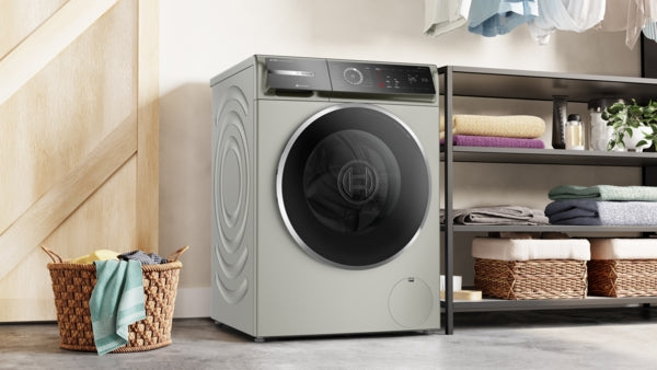 Pearl steel compact front load washer in modern laundry room with shelves, baskets, and folded linens nearby