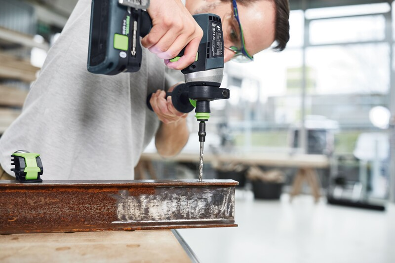 Cordless drill with spiral HSS bit drilling into rusted metal beam for power tool accessories and home improvement