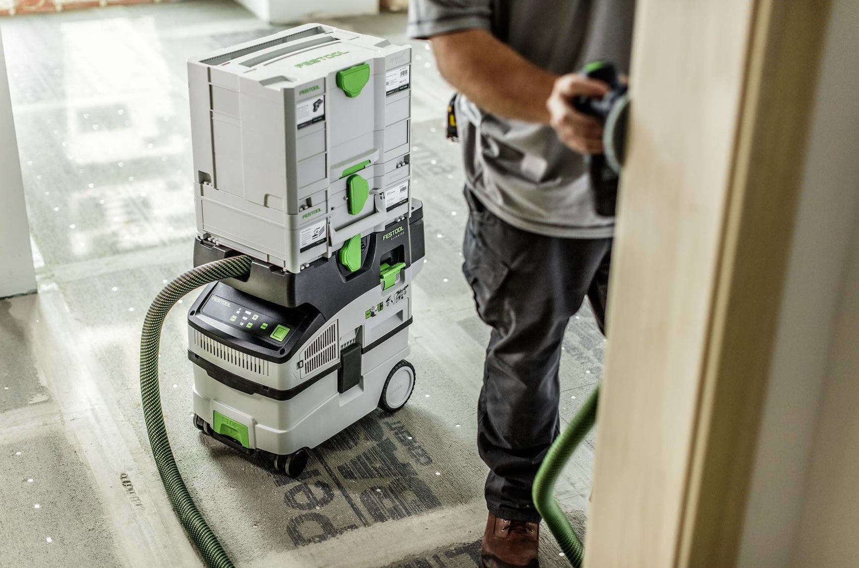 Cordless mobile dust extractor with stacked Festool storage boxes on concrete floor in woodworking tools setting