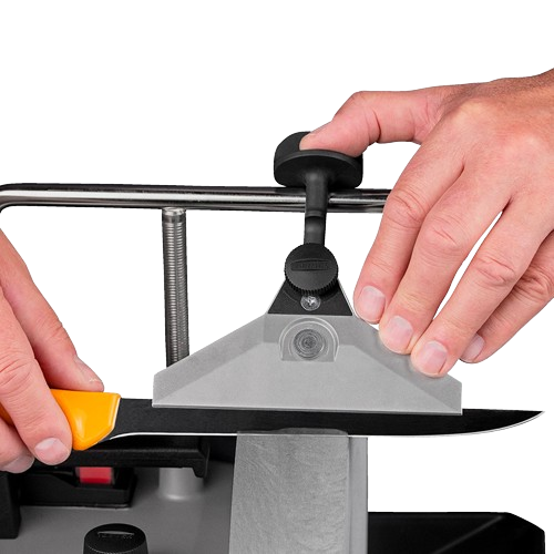 Hand adjusting wide centering jig to position knife blade for sharpening on grinding tool in home improvement use