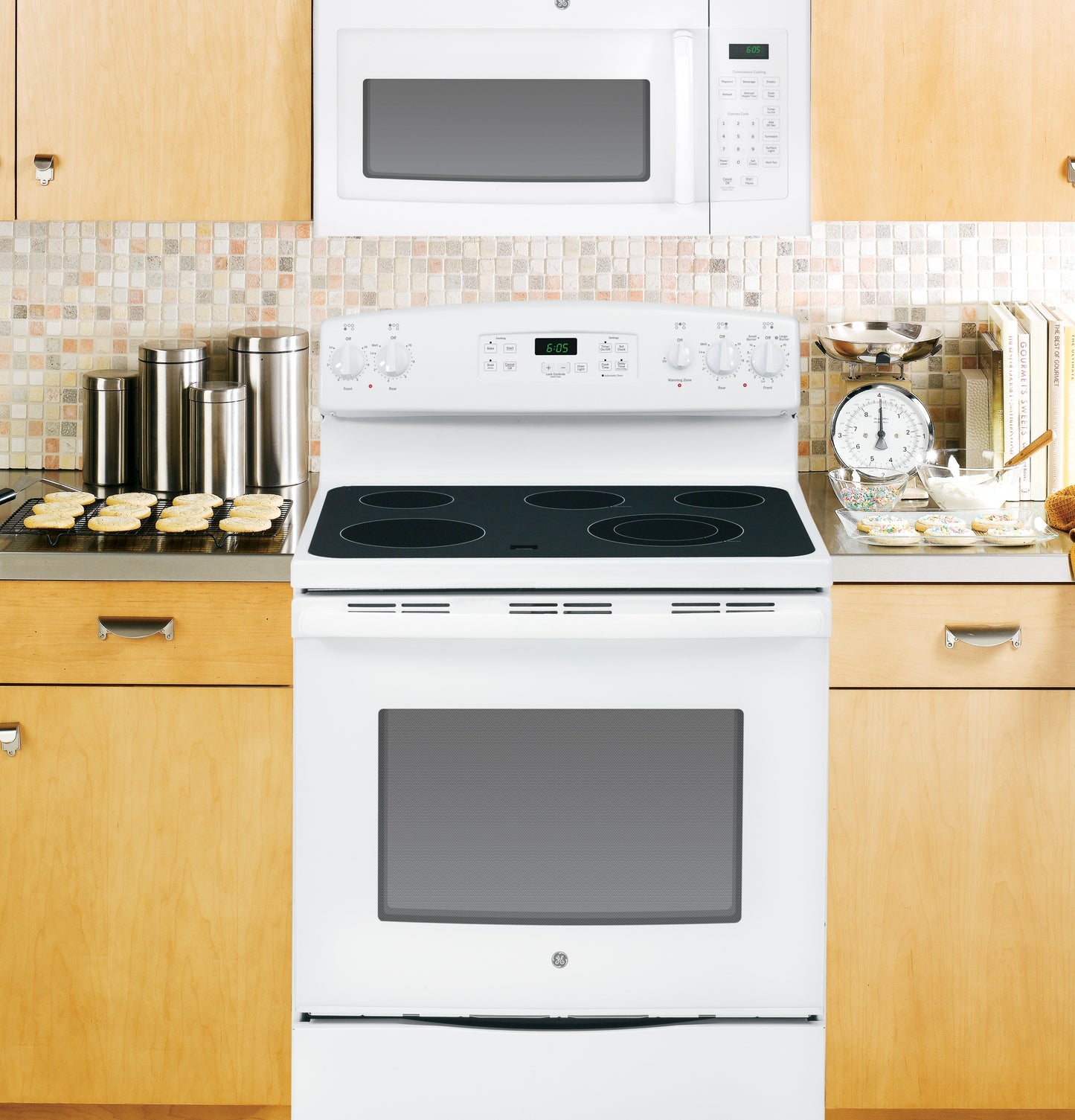White over-the-range microwave above white electric stove in kitchen with wooden cabinets and mosaic tile backsplash