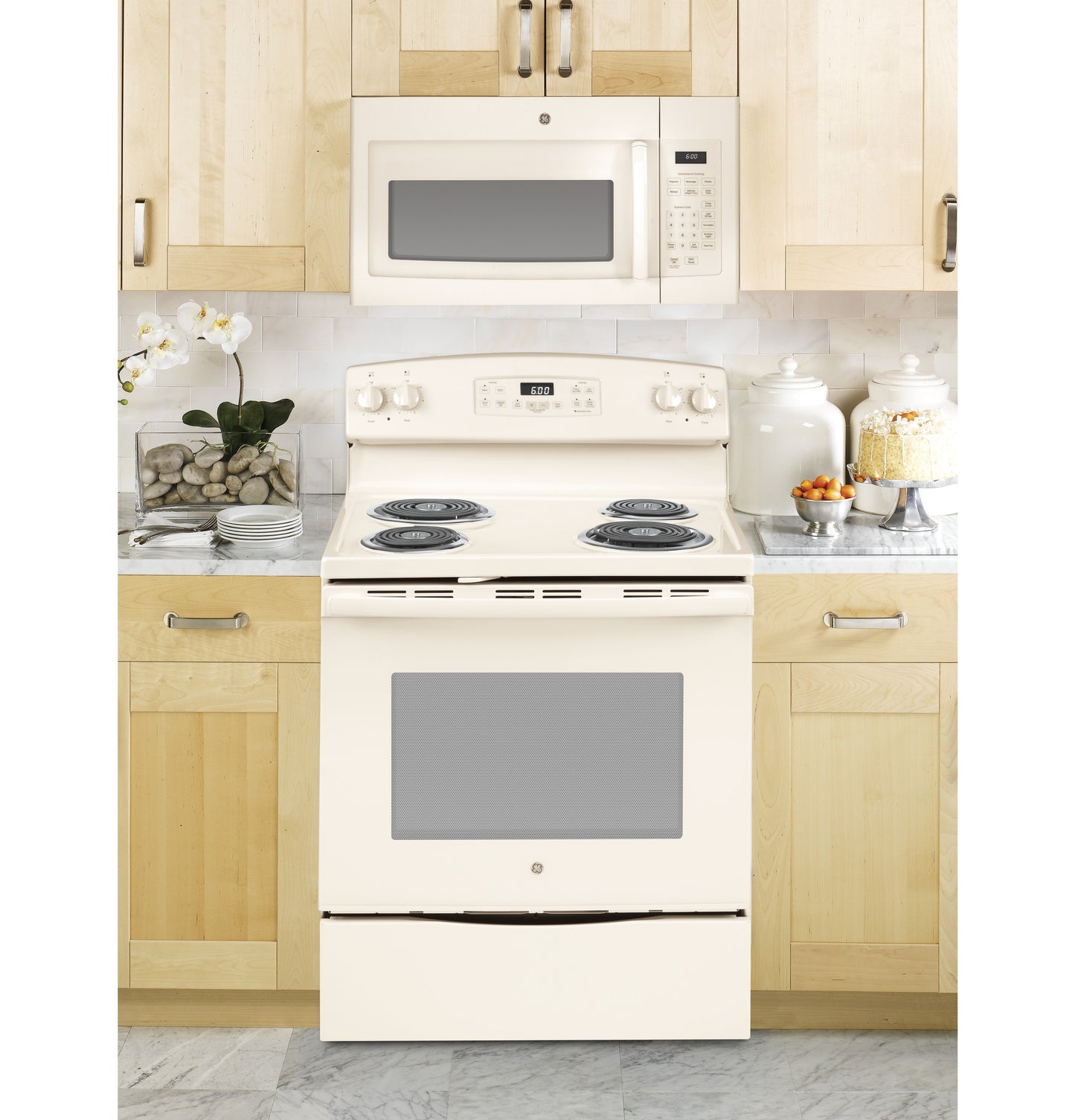 Cream-colored over-the-range microwave above matching electric stove in kitchen appliances and cookware setting