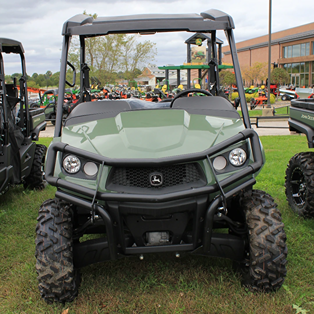 Green mid-size utility vehicle with rugged Maxxis Bighorn tires parked on grass at outdoor equipment display