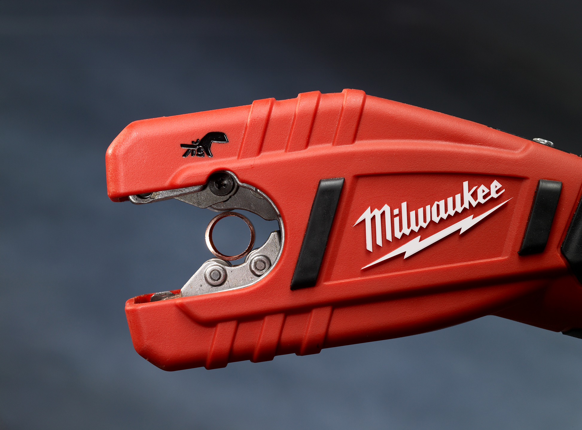 Close-up of a red cordless tubing cutter tool for plumbing with Milwaukee branding on the handle
